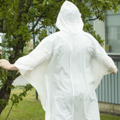 En bild på en person med vit poncho. Bilden leder till urval regnponchos i vår webbshop.